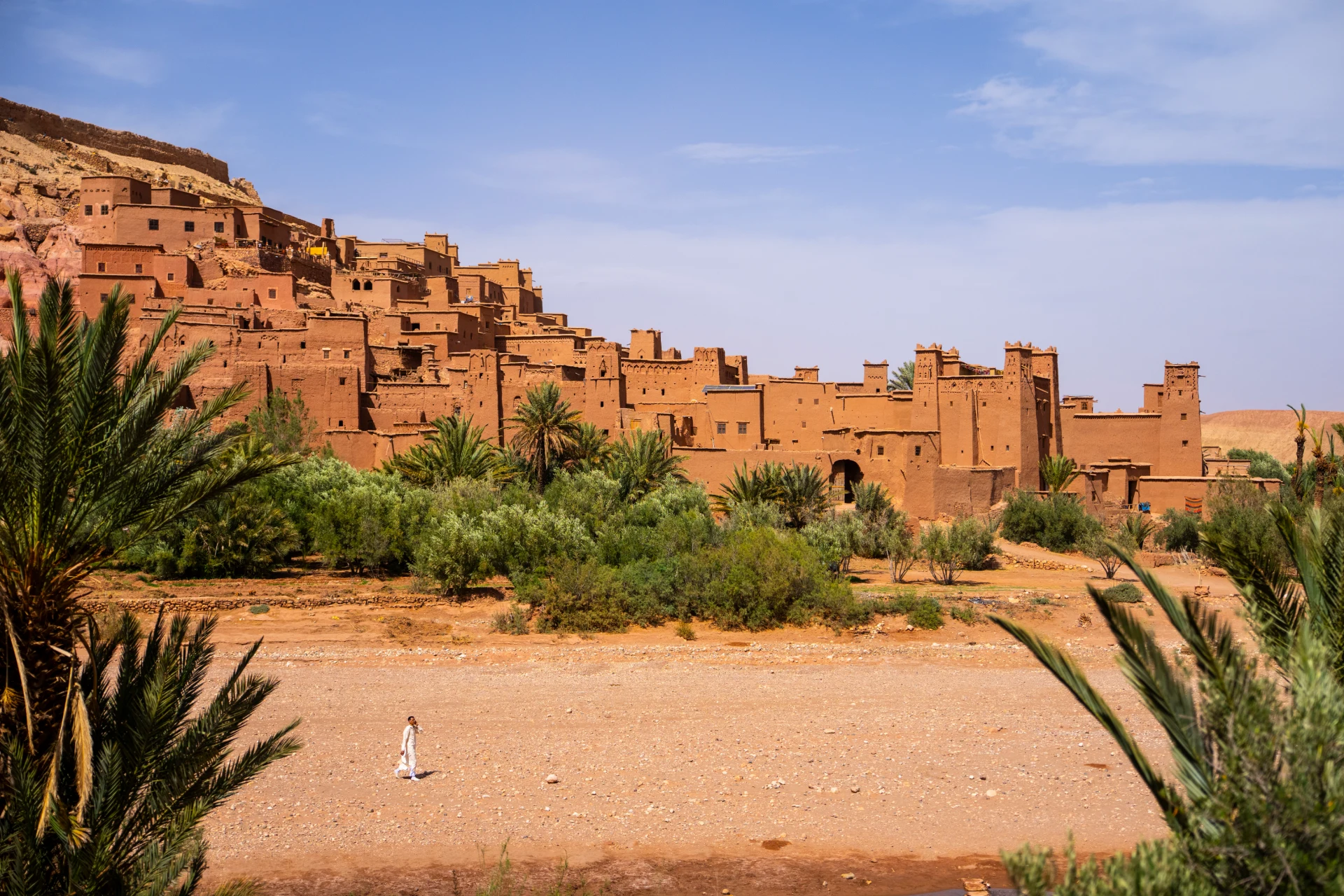 Ait Ben Haddou kasbah seen across the dry riverbed with palm trees
