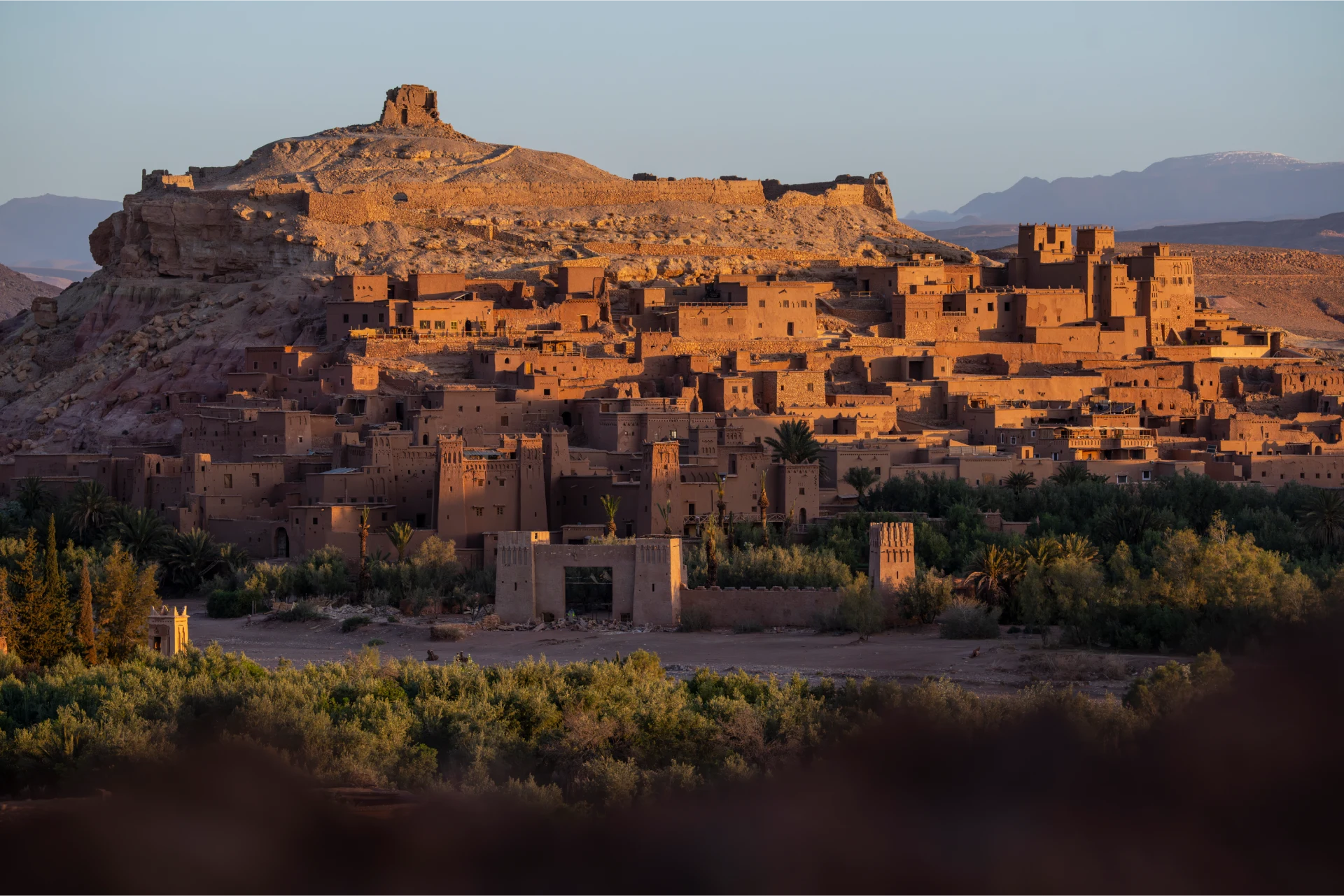 Ait Ben Haddou kasbah glowing at golden hour with the Ounila valley below