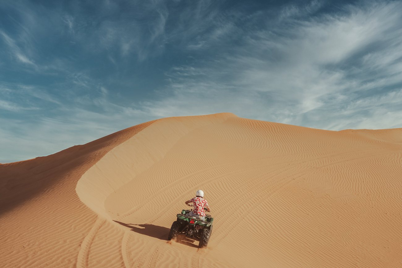A traveler sitting alone on a Sahara dune at sunset